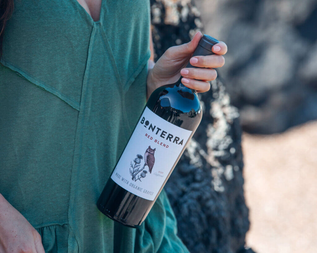 woman in green holding a bottle of wine